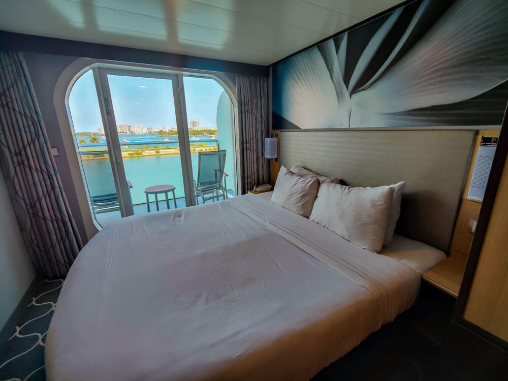 queen bed next to glass doors that lead out to ocean view balcony