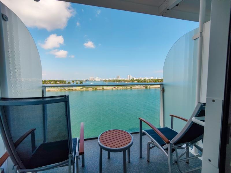 Photo shows the balcony of a Symphony of the Seas stateroom. Includes two longe chairs, two footrests, one small table, partitions on both sides, and ocean view. 