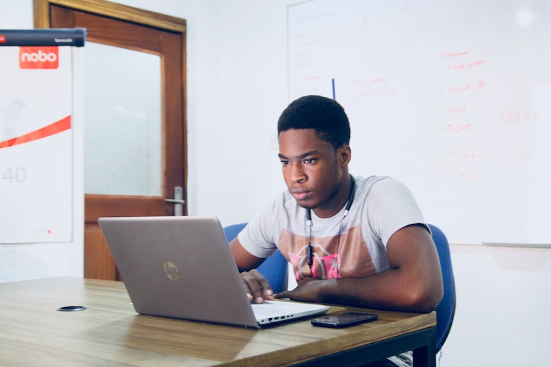 A man sits at a table working on a laptop