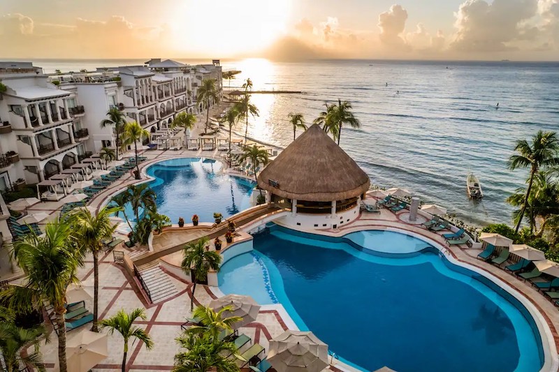 Aerial photo of the Wyndham Alltra Playa del Carmen, an adults only all inclusive resort. Picture shows the Wyndham's swimming pool, side of the building, palm trees, and the ocean