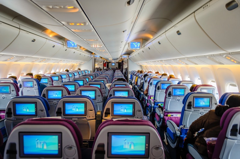 The inside of an airplane. Two seats each by the windows and three in the middle