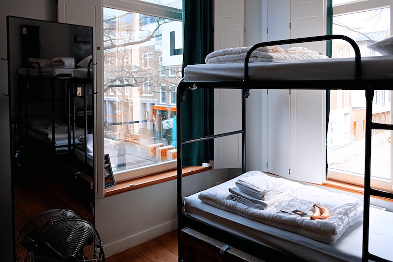 bunk beds next to large windows looking out at the city. Working at a hostel is a good job that travels with no expeience