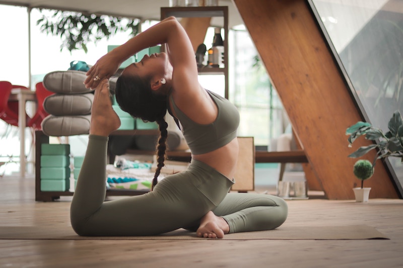 A woman in a yoga pose wearing a forest green top and leggings