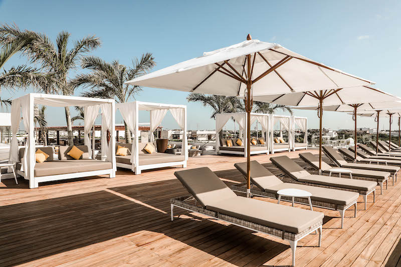 Roof photo of The Reef 28 adults-only all-inclusive resort in downtown Playa del Carmen. Pictures features sun loungers with umbrellas, cabanas, and wooden paneled floors