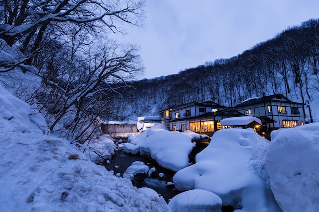 A small house lit up is surrounded by snow and trees in the winter in Akita, Japan