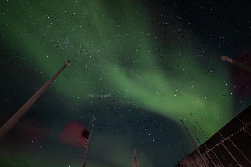 faint yellow southern lights flow over the south pole statio in antarctica like a river
