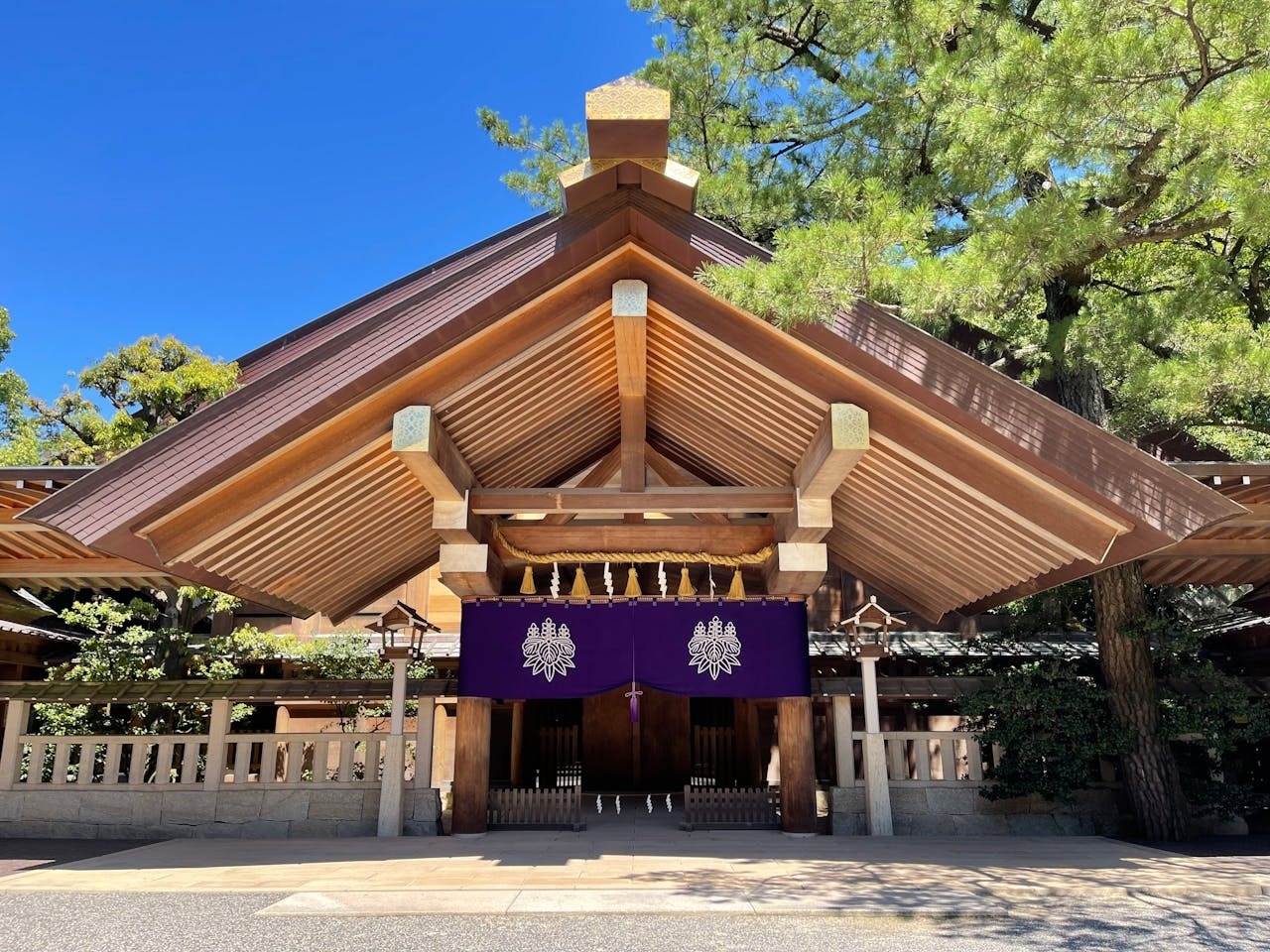 A photo of Atsuta Shrine in Nagoya. The large wooden building has two lanterns in front and purple curtains in the entrance