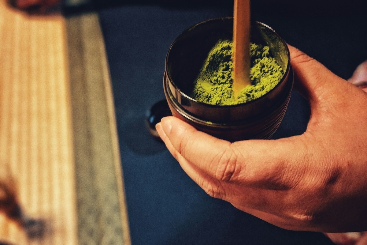 A person hold a cup of matcha green tea powder