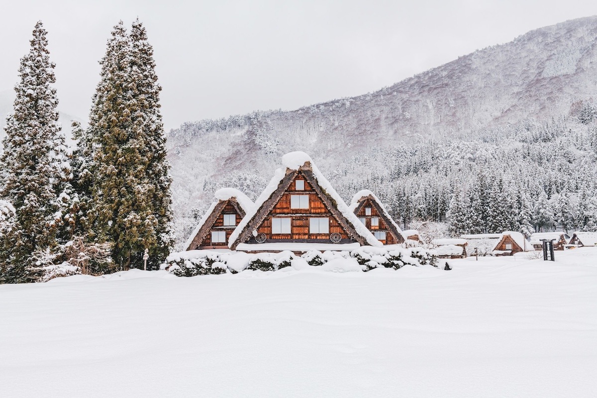 Popular Nagoya day trip destination Shirakawa-go in winter after snowfall. The traditional homes with triangular roos are covered in snow with the mountain in the background