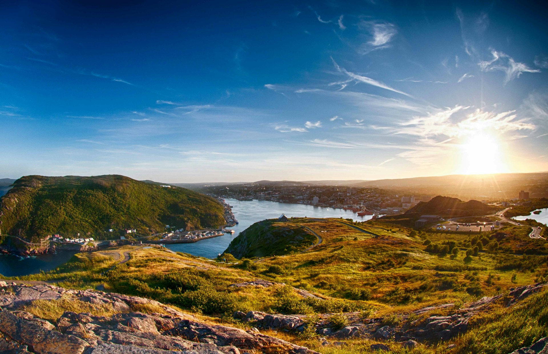 The sun over autumn-colored hills with a winding river cutting through